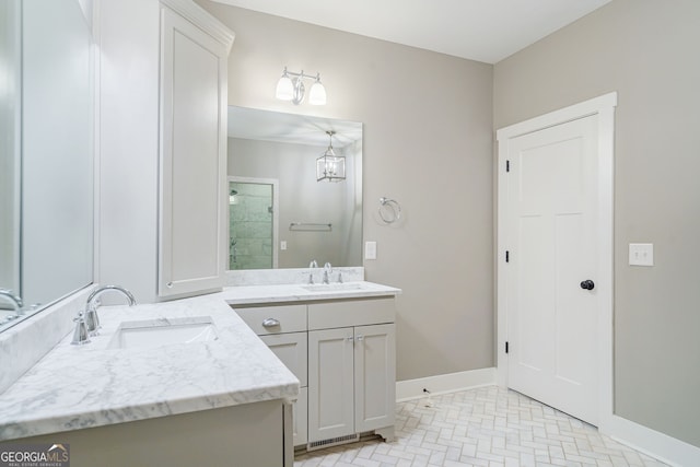 bathroom with a stall shower, two vanities, a sink, and baseboards