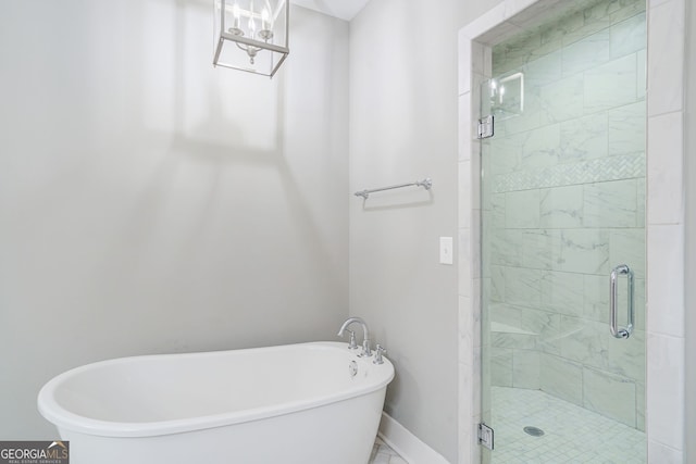 full bathroom with a shower stall, baseboards, and a soaking tub