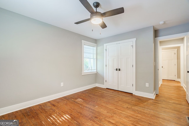 unfurnished bedroom featuring a closet, baseboards, light wood finished floors, and ceiling fan