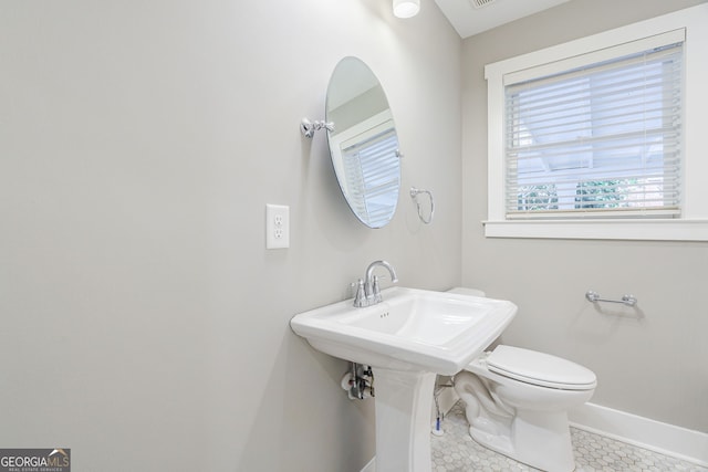 bathroom with toilet, baseboards, and tile patterned flooring