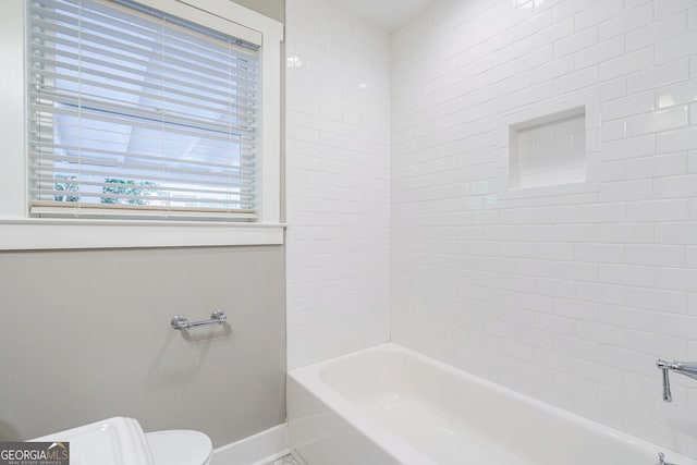 bathroom with tiled shower / bath combo and toilet