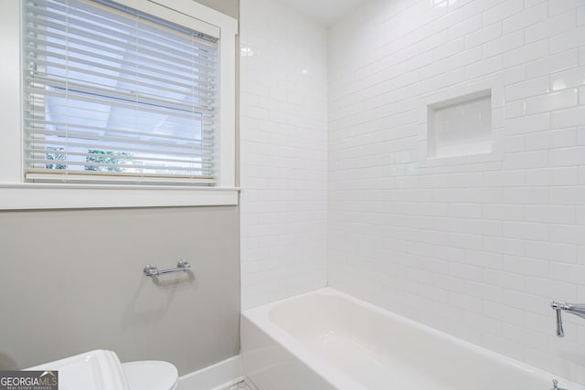 bathroom with toilet, baseboards, and  shower combination