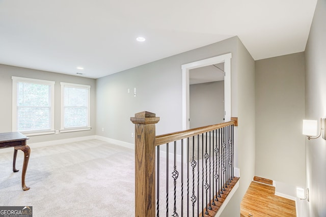 corridor featuring baseboards, an upstairs landing, recessed lighting, and light carpet