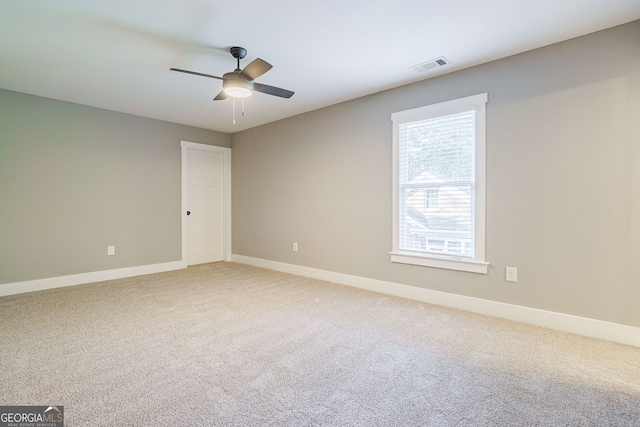 carpeted spare room featuring visible vents, baseboards, and a ceiling fan
