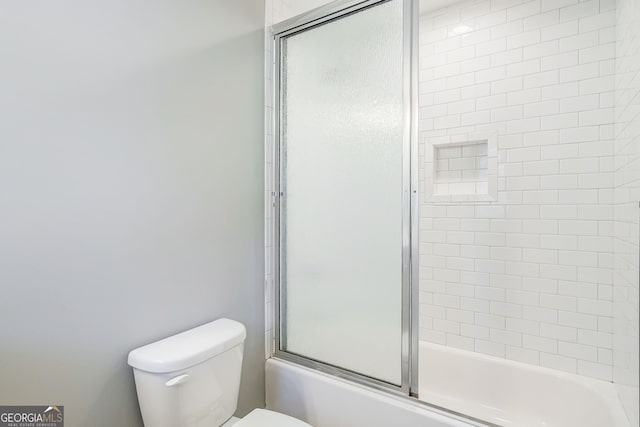 bathroom featuring toilet and combined bath / shower with glass door