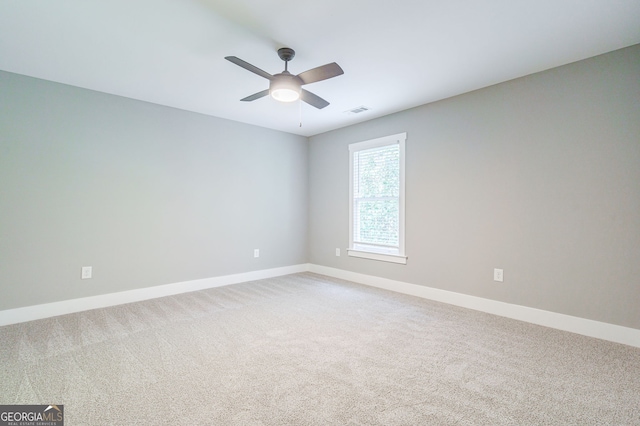 empty room featuring light carpet, visible vents, baseboards, and a ceiling fan