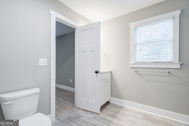 bathroom featuring toilet, vanity, wood finished floors, and baseboards