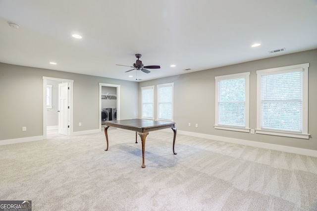 recreation room with separate washer and dryer, light colored carpet, a ceiling fan, visible vents, and baseboards
