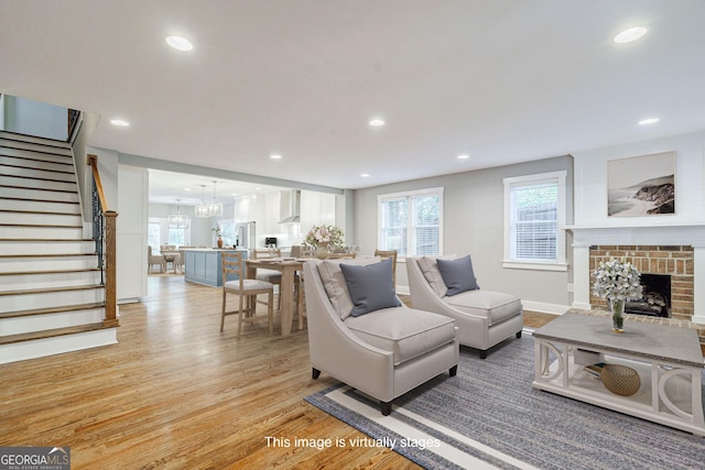 living room with a chandelier, a fireplace, and light hardwood / wood-style flooring