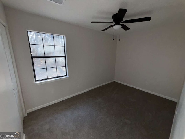 spare room with dark colored carpet, plenty of natural light, and ceiling fan