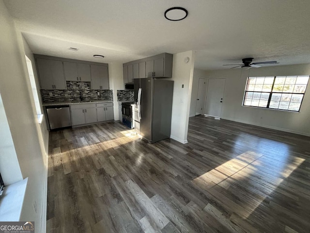 kitchen with gray cabinetry, ceiling fan, dark hardwood / wood-style floors, appliances with stainless steel finishes, and tasteful backsplash