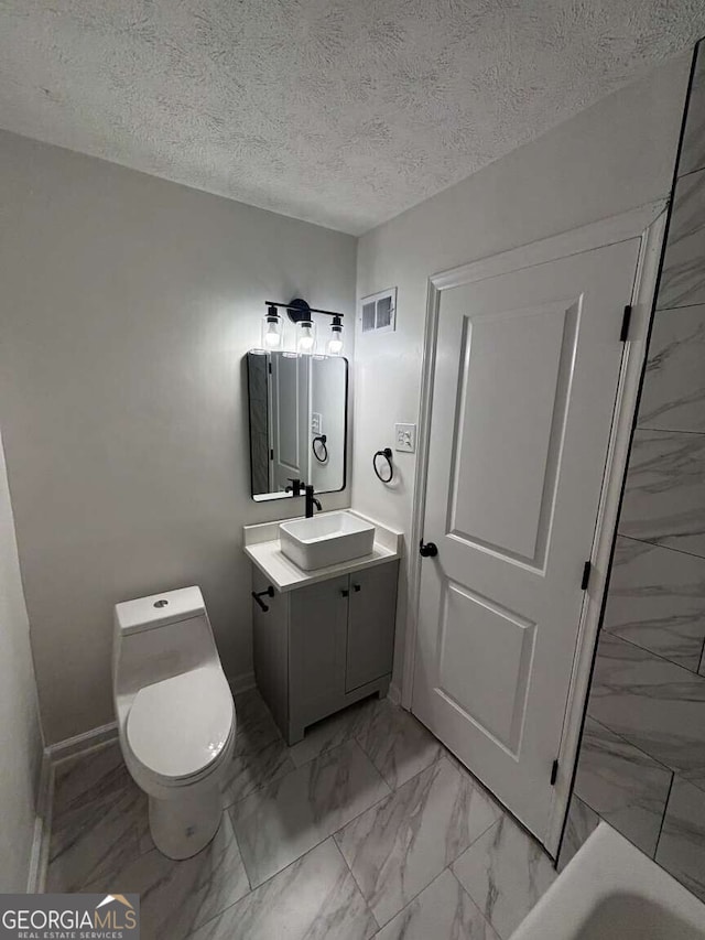 bathroom with vanity, toilet, and a textured ceiling