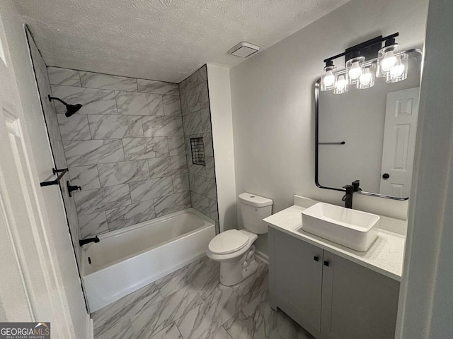 full bathroom with a textured ceiling, vanity, toilet, and tiled shower / bath