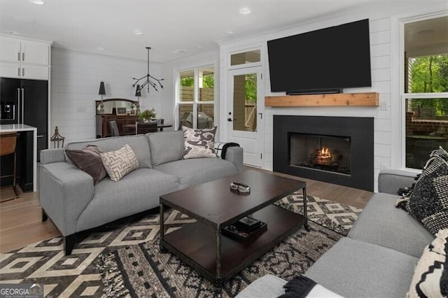 living room featuring a large fireplace, ornamental molding, a chandelier, and dark hardwood / wood-style floors