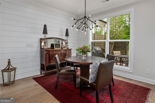 dining room featuring an inviting chandelier, wooden walls, and wood-type flooring