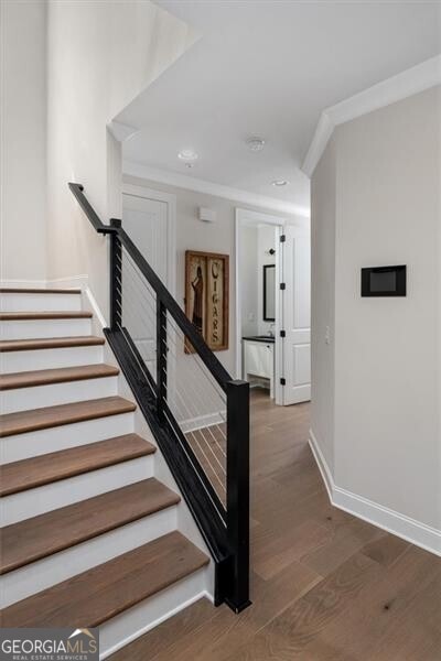 stairway featuring hardwood / wood-style flooring and ornamental molding