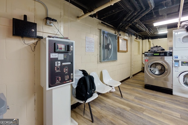 clothes washing area with washing machine and clothes dryer, hardwood / wood-style floors, and stacked washer / drying machine