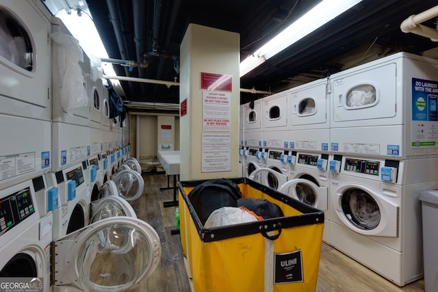 clothes washing area with wood-type flooring, separate washer and dryer, and stacked washer / drying machine