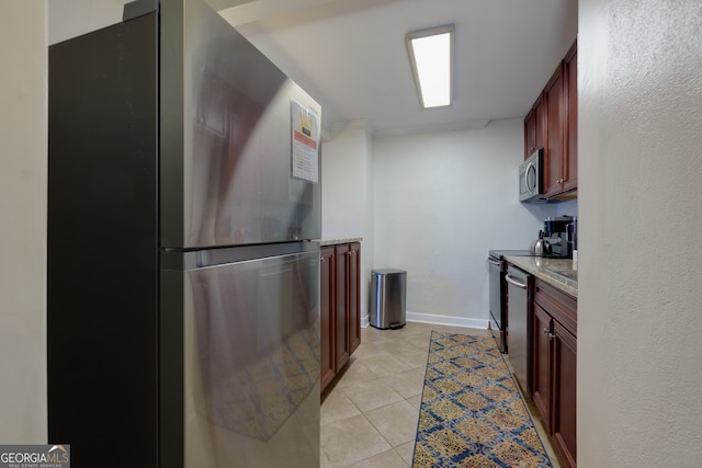 kitchen featuring light stone counters, light tile patterned floors, and stainless steel appliances