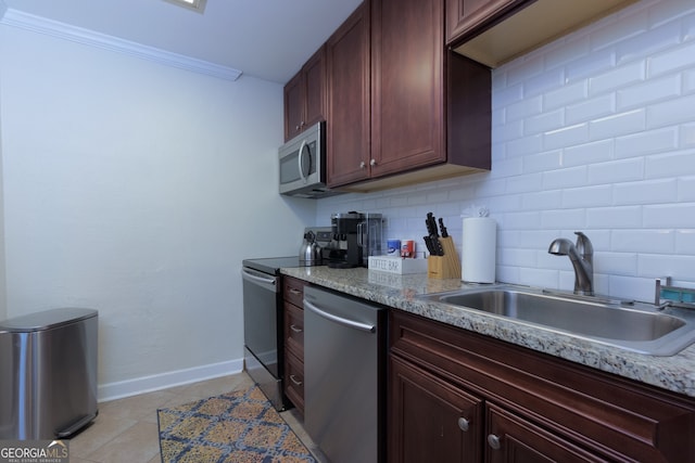 kitchen featuring light stone counters, sink, stainless steel appliances, and ornamental molding