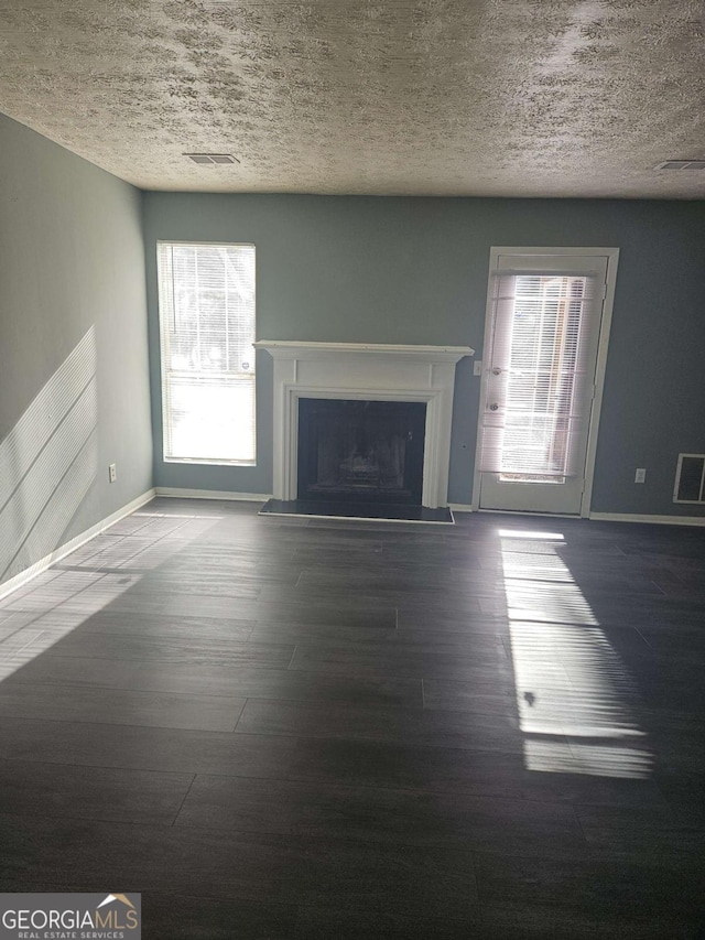 unfurnished living room featuring dark hardwood / wood-style flooring and a textured ceiling