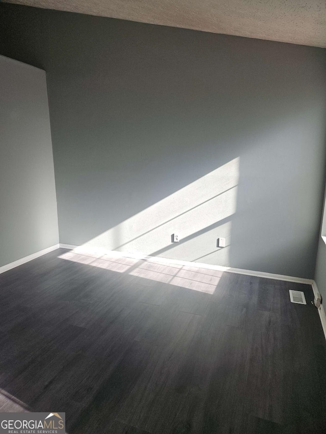 unfurnished room featuring wood-type flooring and a textured ceiling