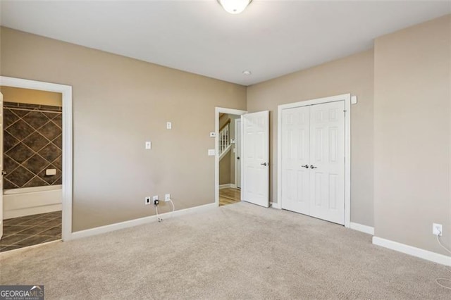 unfurnished bedroom featuring carpet, ensuite bathroom, and a closet