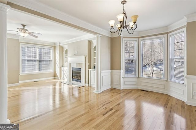 unfurnished living room featuring built in shelves, ceiling fan with notable chandelier, light hardwood / wood-style floors, and ornamental molding