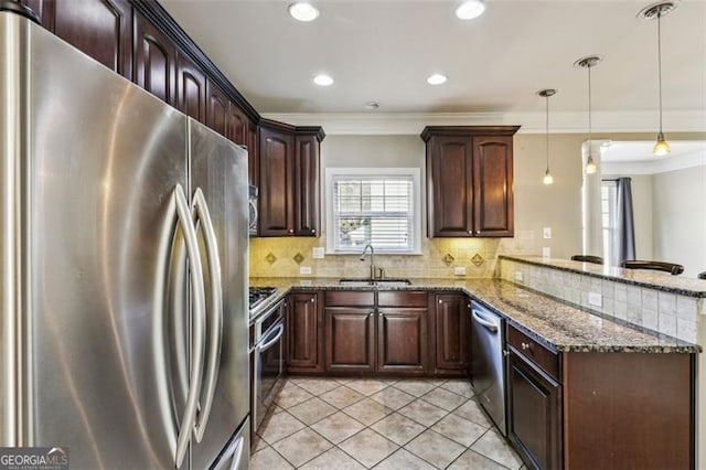 kitchen with kitchen peninsula, appliances with stainless steel finishes, ornamental molding, sink, and hanging light fixtures