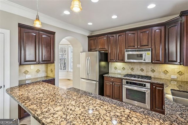 kitchen with hanging light fixtures, stainless steel appliances, dark stone countertops, crown molding, and decorative backsplash