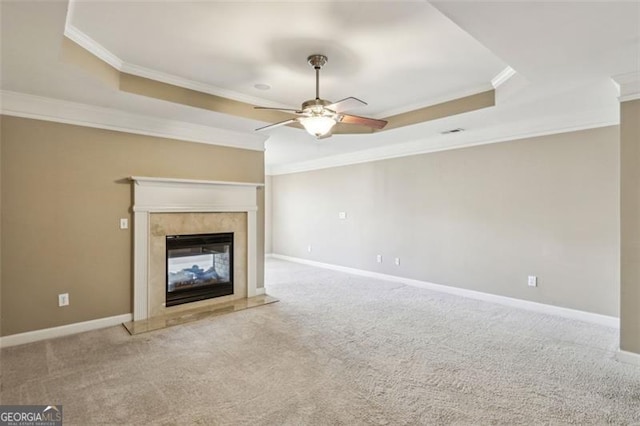 unfurnished living room with a high end fireplace, light colored carpet, a raised ceiling, and crown molding