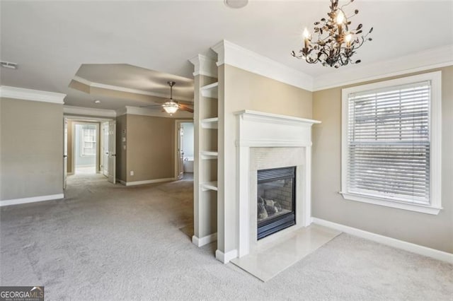 unfurnished living room with ceiling fan with notable chandelier, a raised ceiling, ornamental molding, and light carpet