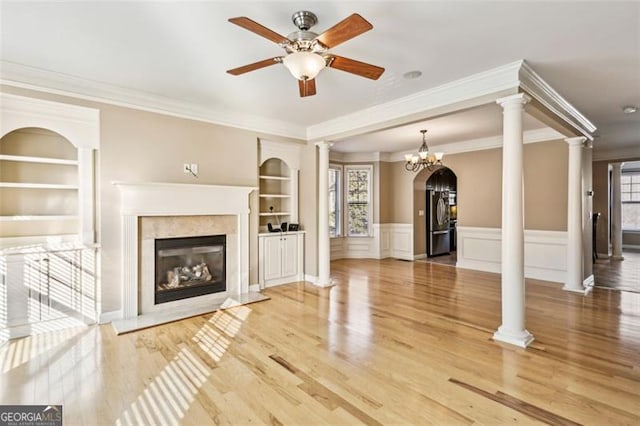 unfurnished living room featuring built in features, ornamental molding, and a premium fireplace