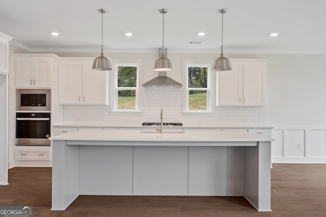 kitchen with crown molding, white cabinetry, an island with sink, and appliances with stainless steel finishes