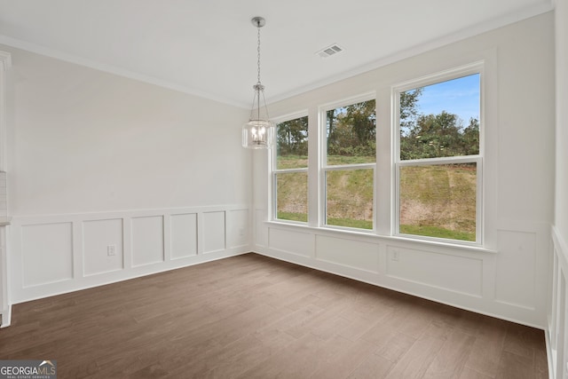 unfurnished dining area featuring dark wood-type flooring, crown molding, a wealth of natural light, and an inviting chandelier