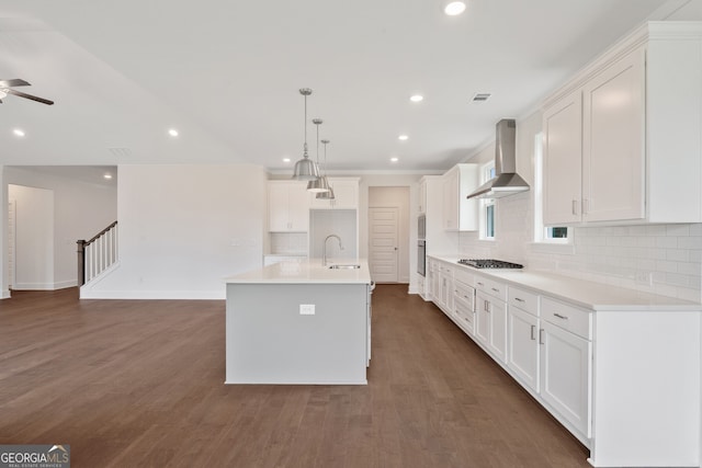 kitchen featuring a center island with sink, white cabinetry, wall chimney exhaust hood, and sink