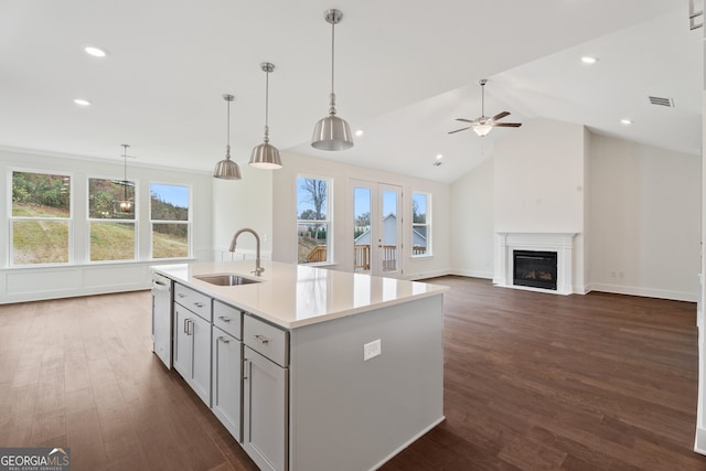 kitchen with ceiling fan, a center island with sink, hanging light fixtures, and sink