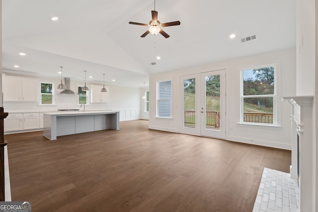 unfurnished living room featuring ceiling fan, dark hardwood / wood-style floors, high vaulted ceiling, and french doors