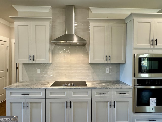 kitchen featuring backsplash, wall chimney exhaust hood, white cabinetry, and stainless steel appliances