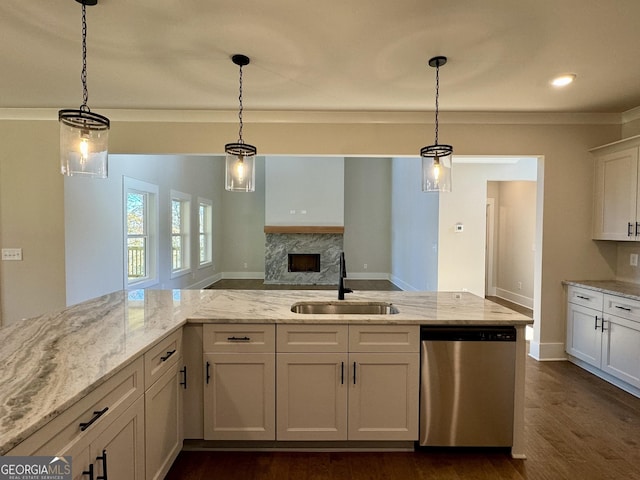 kitchen featuring light stone counters, stainless steel dishwasher, sink, pendant lighting, and white cabinetry