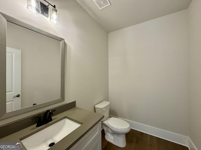 bathroom with hardwood / wood-style floors, vanity, and toilet