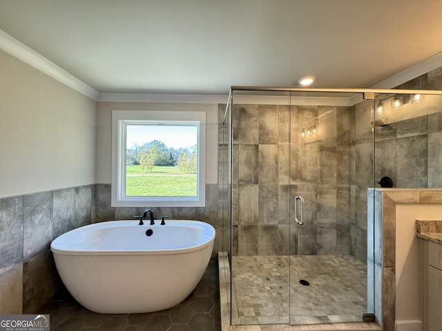 bathroom with separate shower and tub, crown molding, vanity, and tile walls