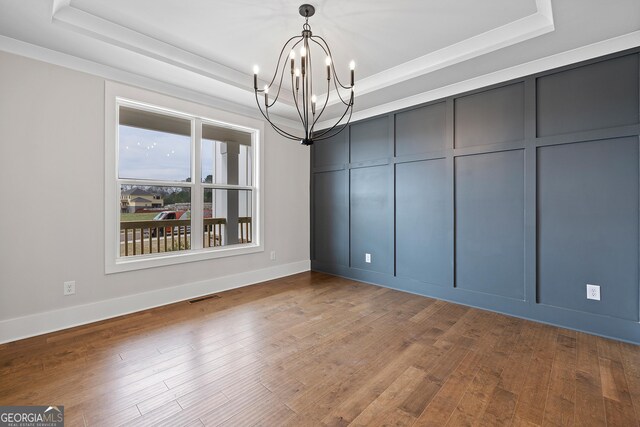 unfurnished dining area featuring a notable chandelier, dark hardwood / wood-style floors, and a tray ceiling