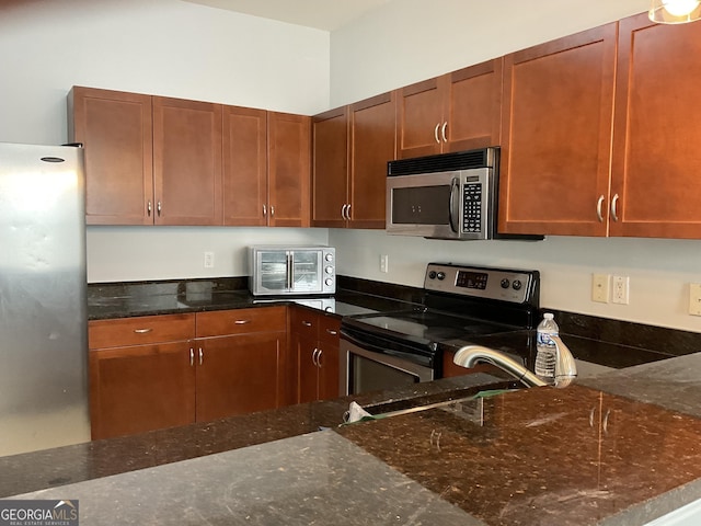 kitchen with appliances with stainless steel finishes, dark stone counters, and sink