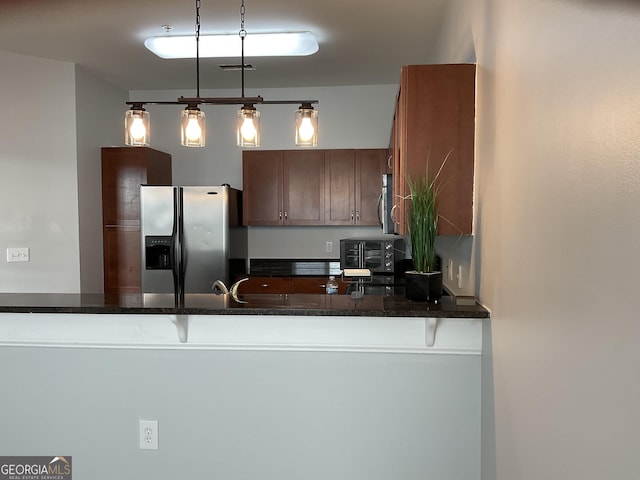 kitchen featuring decorative light fixtures, dark stone countertops, kitchen peninsula, and stainless steel refrigerator with ice dispenser