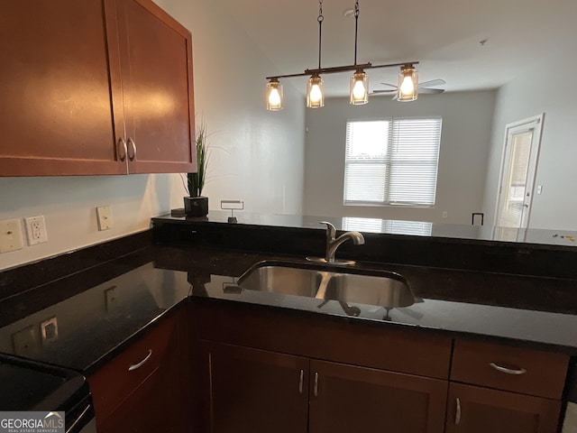 kitchen with decorative light fixtures, dark stone countertops, and sink