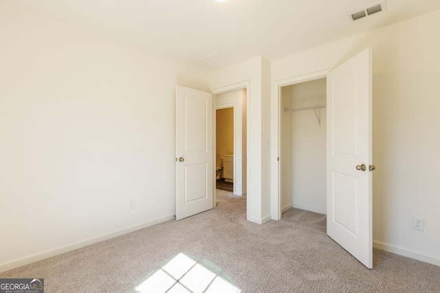 unfurnished bedroom featuring light carpet and a closet