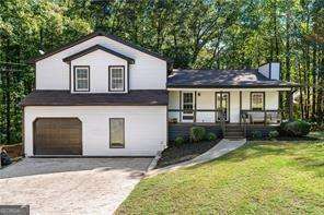 tri-level home with a front lawn, covered porch, and a garage