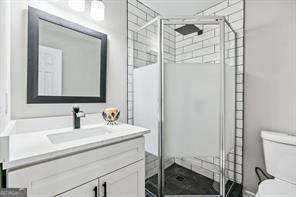 bathroom with vanity, toilet, and a shower with door