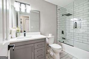 full bathroom with vanity, toilet, and enclosed tub / shower combo